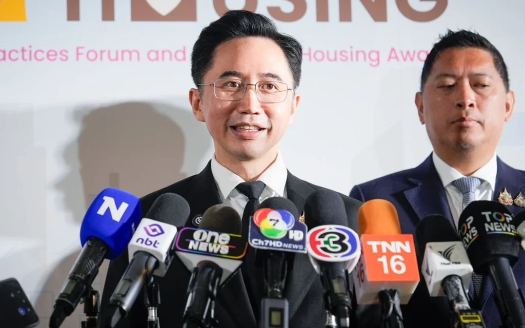 Two officials speak to reporters behind a row of microphones.