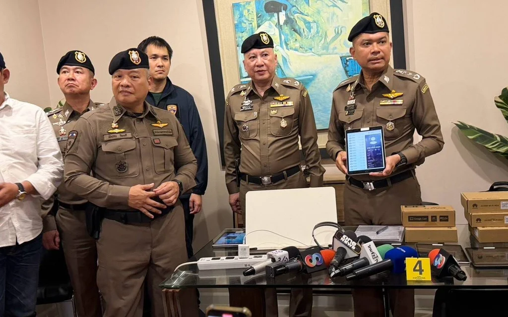 Police officers hold a press briefing beside seized electronic equipment.