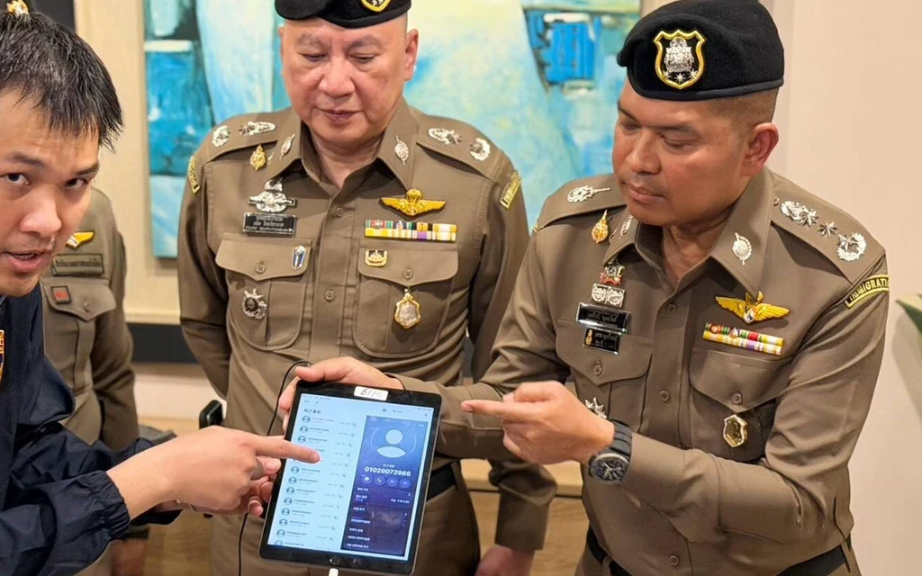 Police officers examine a tablet during an immigration police briefing.