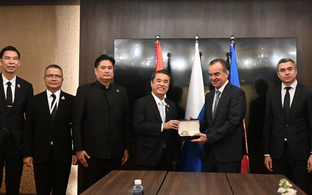 Officials from Thailand and Russia pose with a commemorative plaque at a meeting.