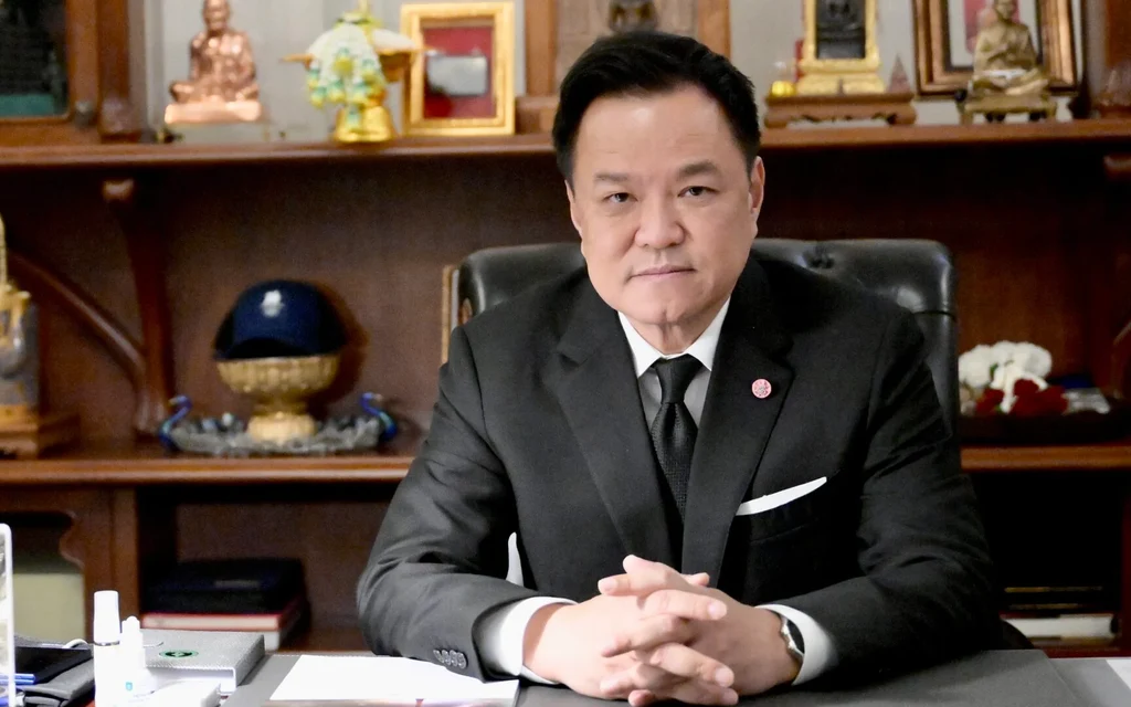 Anutin sits at a desk in an office surrounded by Buddhist objects.