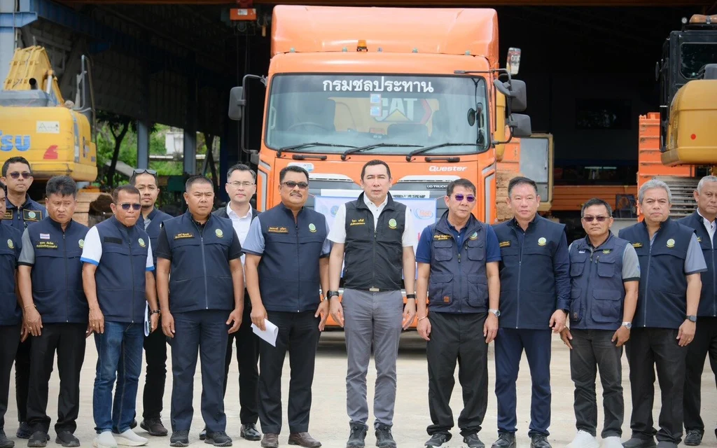 Officials pose in front of trucks and construction equipment.