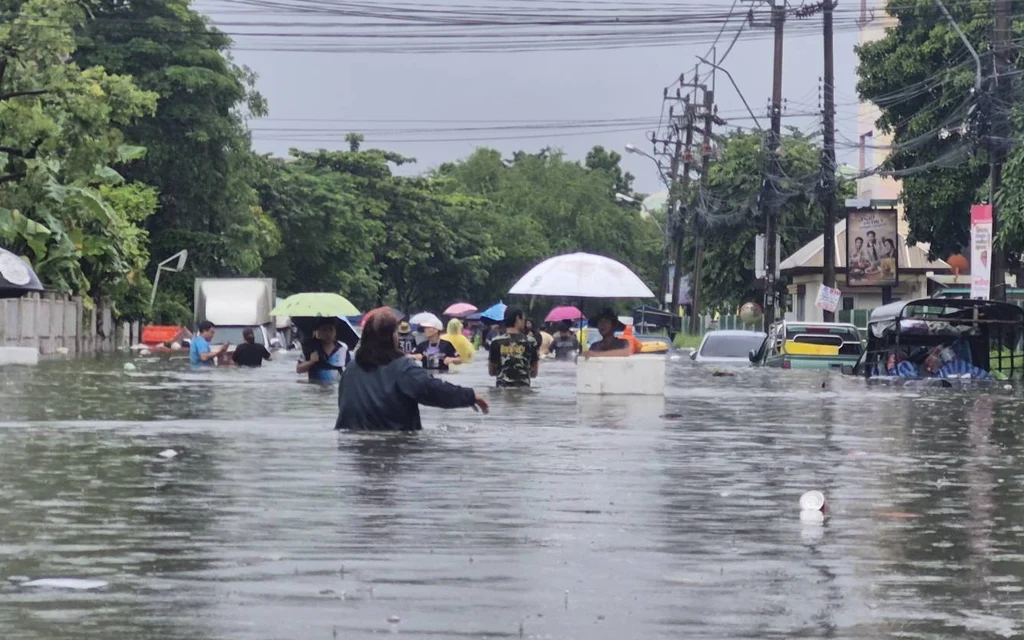 People walking through a flooded street during heavy rain.