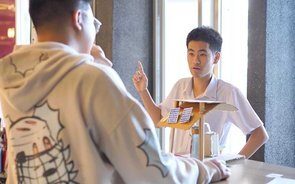 Two students discussing a sustainability project model.