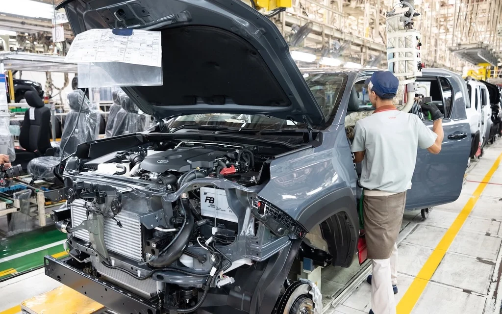Workers assemble vehicles on an automotive factory production line.