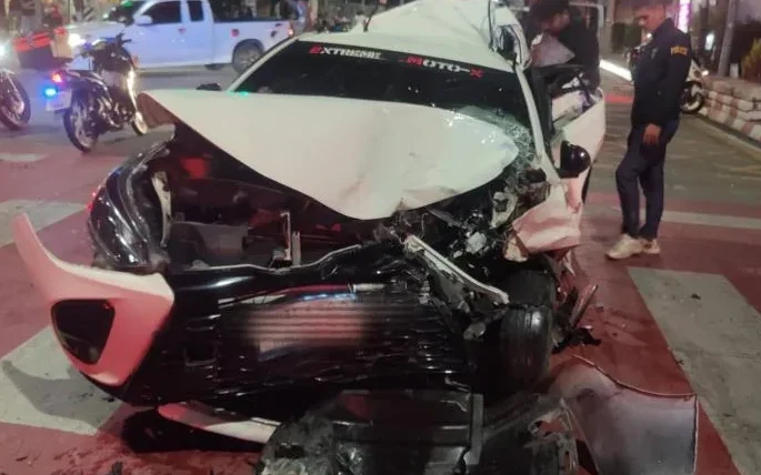 Heavily damaged car at a nighttime crash scene with police nearby.