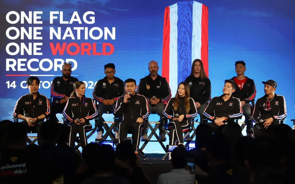 Group of people on stage with a large flag backdrop.