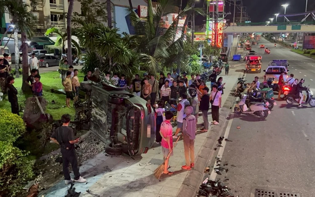 Overturned vehicle at roadside as bystanders and emergency responders gather at night