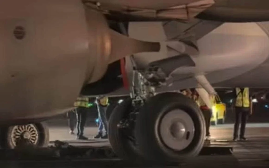 Airplane landing gear and ground crew on a nighttime runway