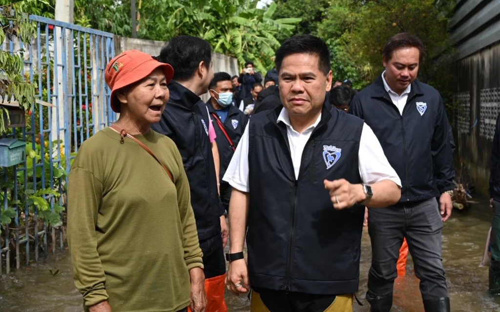 Thai minister inspecting flood-affected area and talking to a local resident.