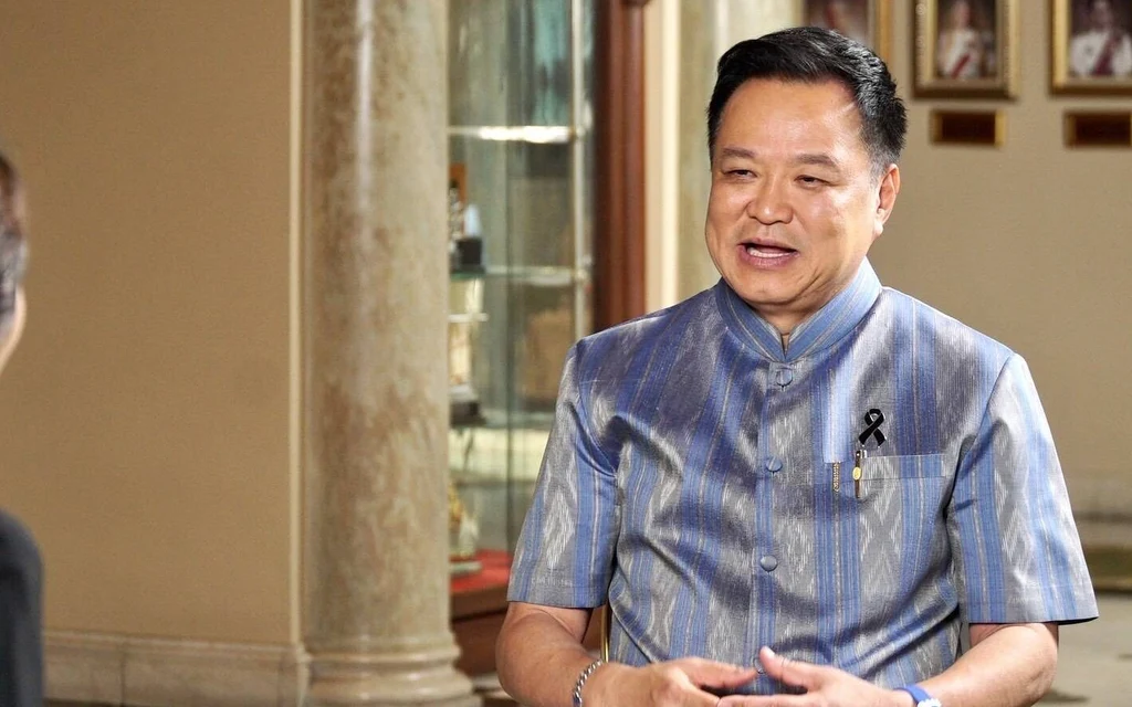 Anutin speaks with an interviewer inside a formal building.