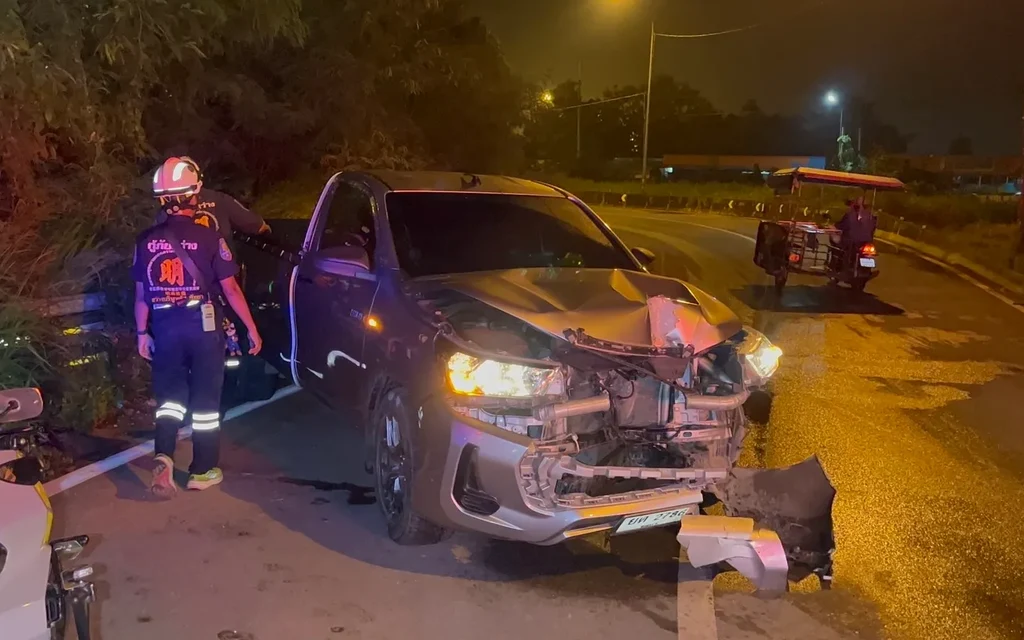 A damaged pickup truck at a night accident scene with rescuers.