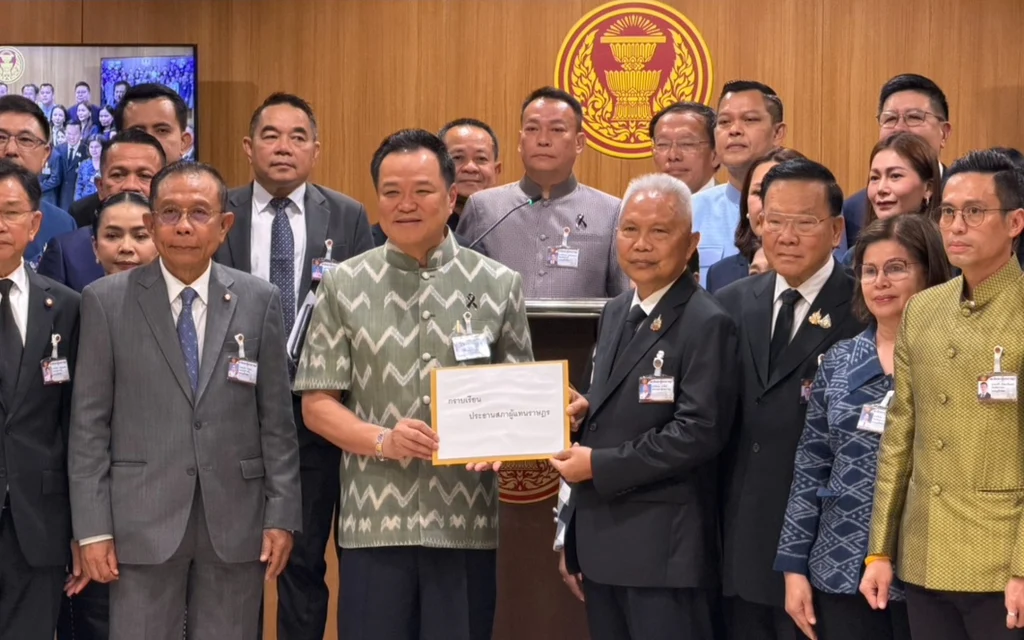 Officials pose with a submitted document before the parliamentary emblem.