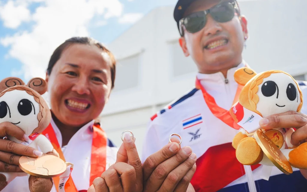 Two Thai archers celebrate their gold medals with mascots.