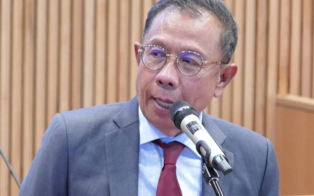 Man in suit speaking into a microphone at an event