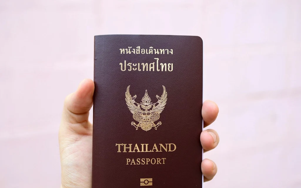 a person holding a thai passport in their hand