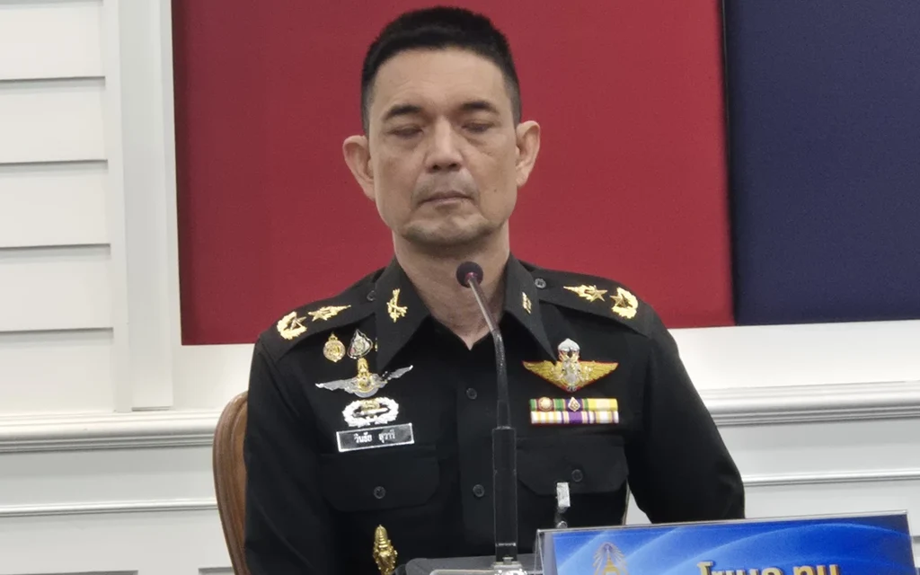 Military officer speaking at a press conference behind a microphone.