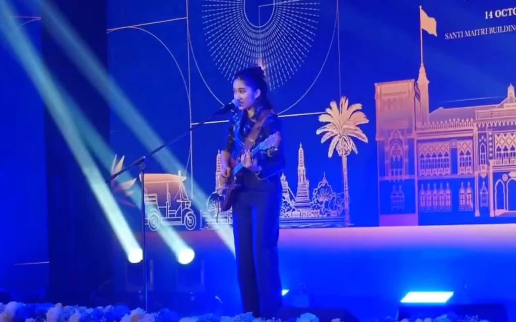 A young woman performing on stage with a guitar.