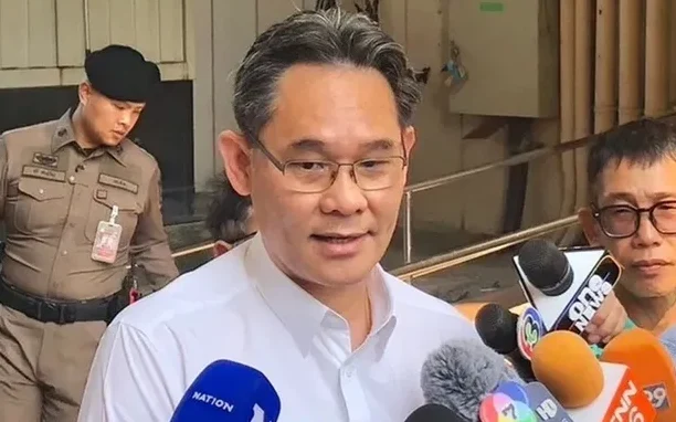 A man speaking to reporters holding multiple microphones.