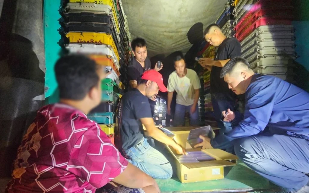 People inspecting boxes of seized vaping devices