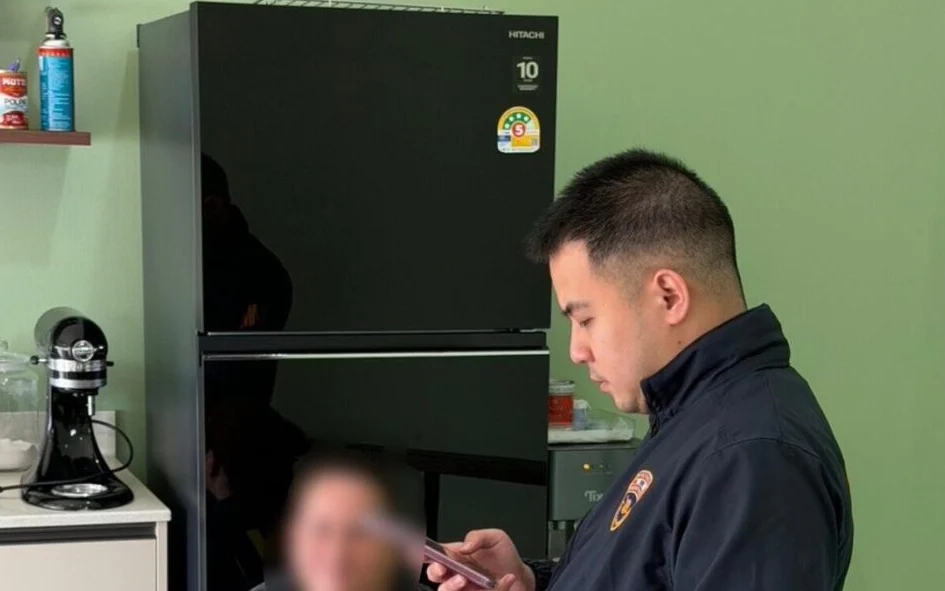An immigration officer interacting with a blurred suspect in a kitchen.