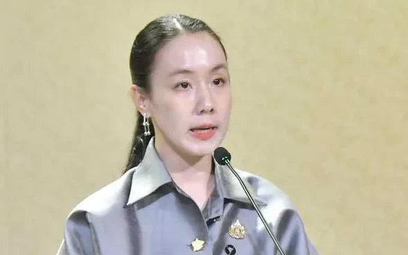 A woman speaks at a microphone during a formal event.