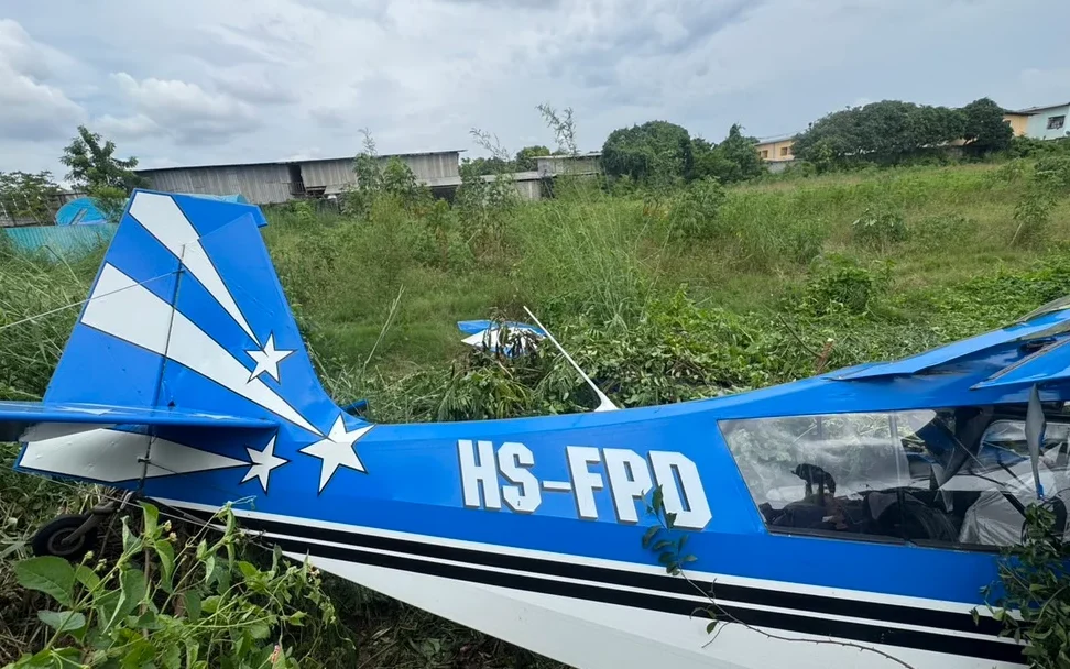 A small blue and white aircraft crashed in a grassy field.