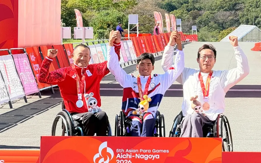 Three wheelchair athletes celebrate with medals at the Asian Para Games.