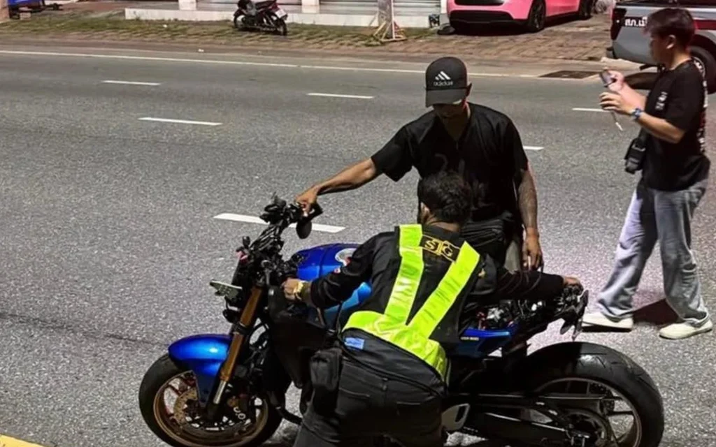 Two people inspecting a blue motorcycle on road