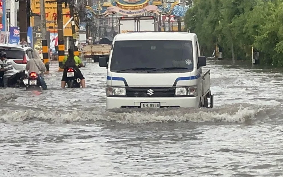 Vehicles and motorcyclists navigate a flooded Pattaya road after heavy rain.