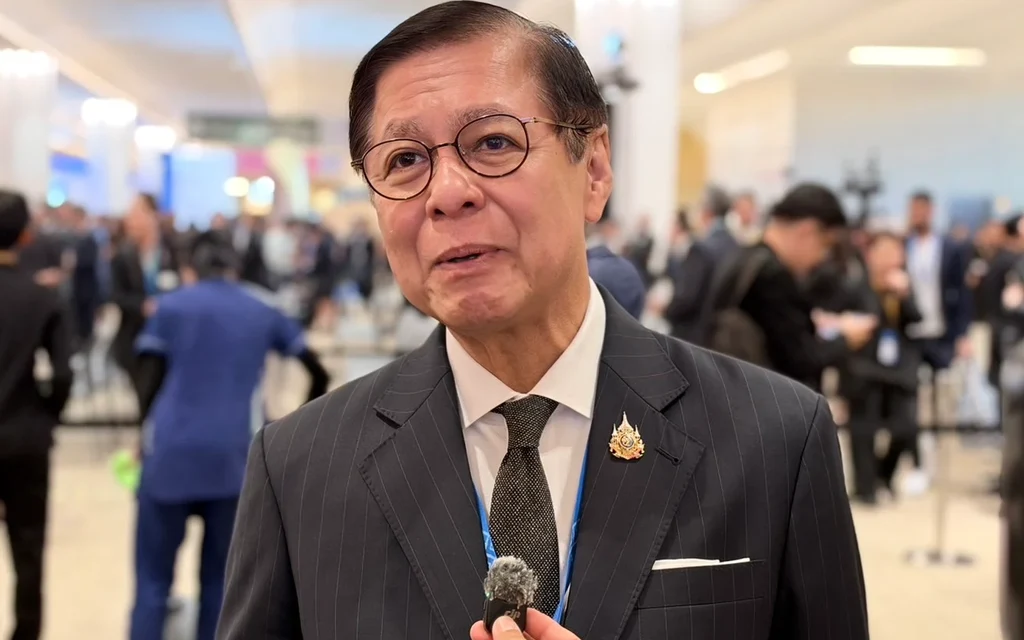 A Thai official speaking to a reporter at an event.