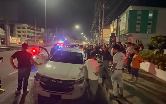 Police and bystanders at a night scene with a white pickup truck.
