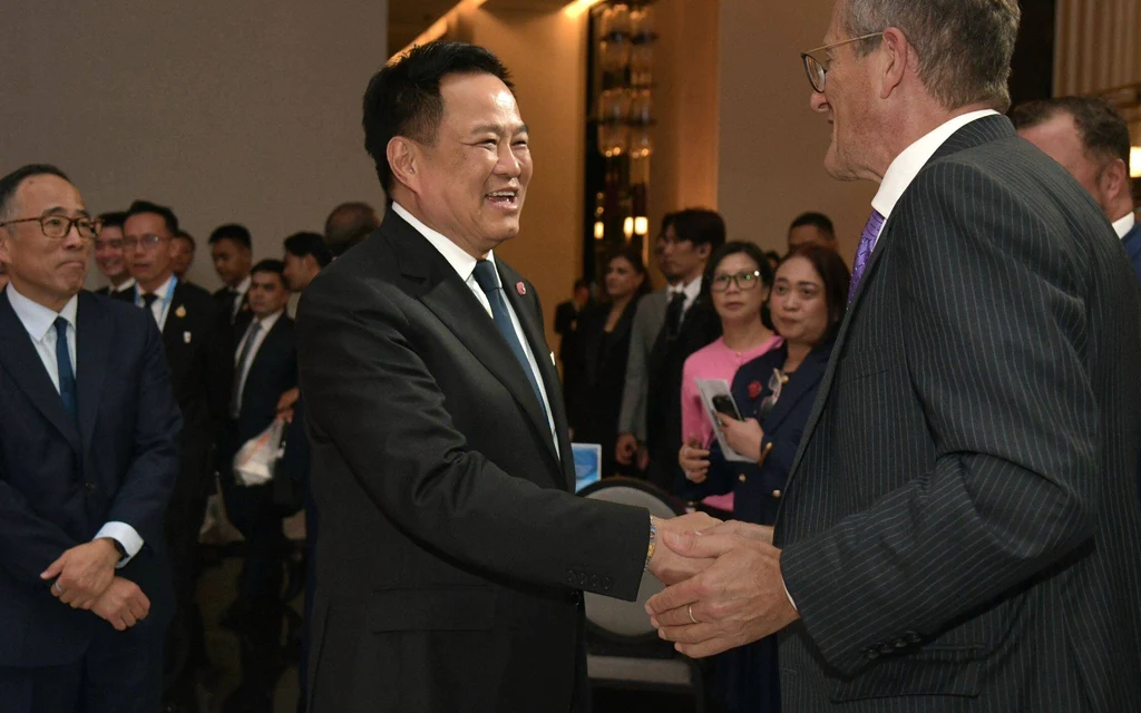 Anutin Charnvirakul shaking hands with a man at a forum.