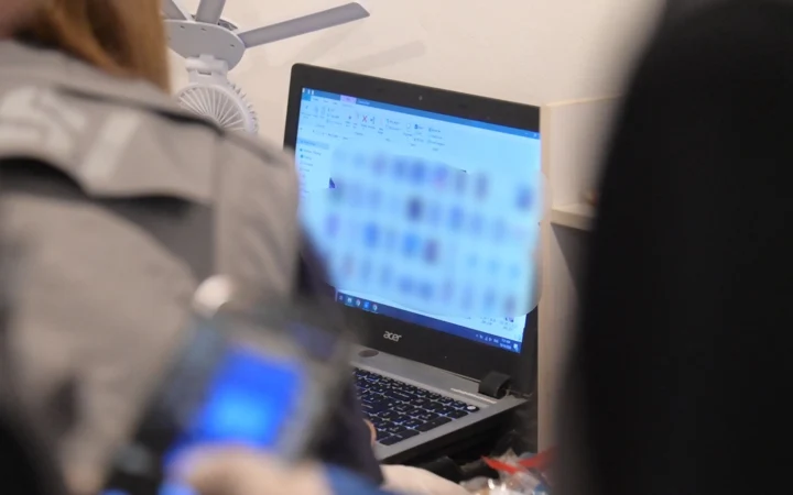 DSI officers investigating a laptop during an arrest operation.