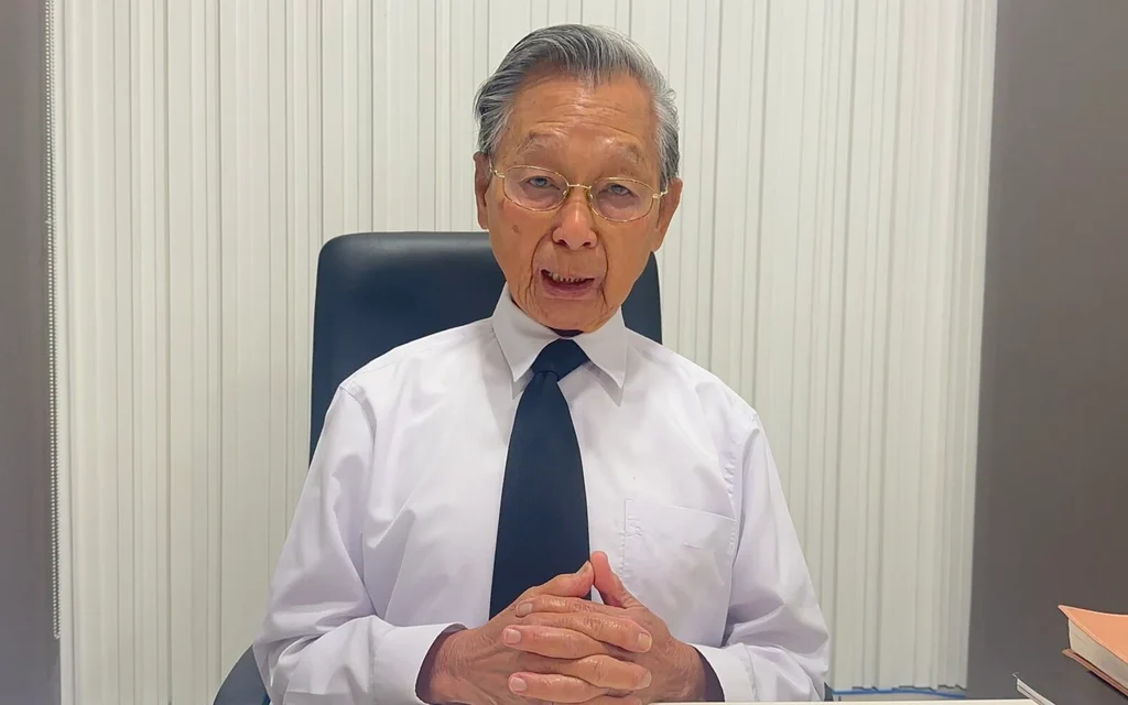 Chuan Leekpai sitting at a desk in a white shirt and tie.