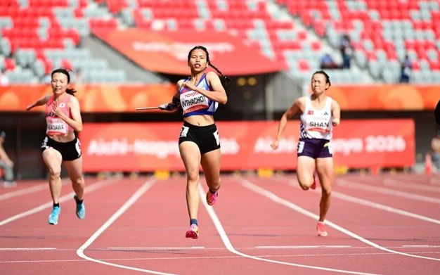 Female sprinters race on a track at an athletics competition.