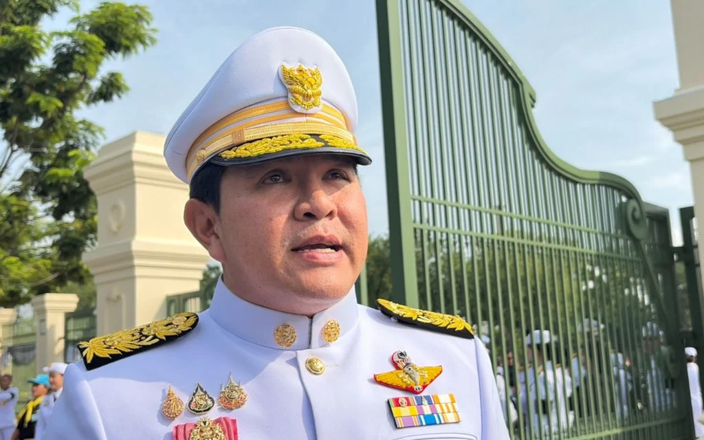 A Thai official in uniform speaking outdoors.