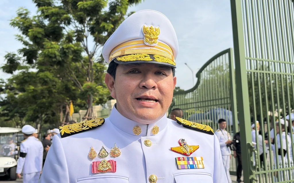 A Thai official in white uniform standing outdoors.
