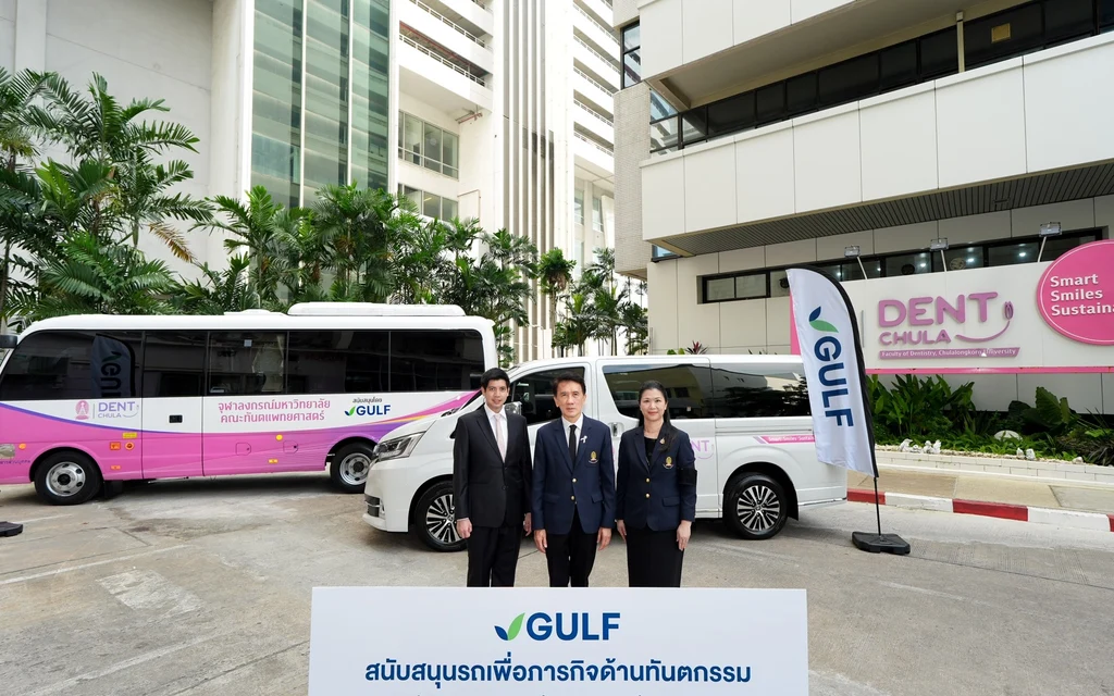 University staff pose outside with donated vehicles and a GULF sign.
