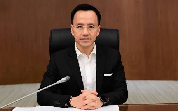 A man in a suit sits at a conference table.