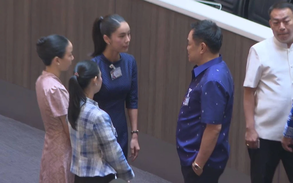 Politicians greet one another inside a parliamentary chamber.