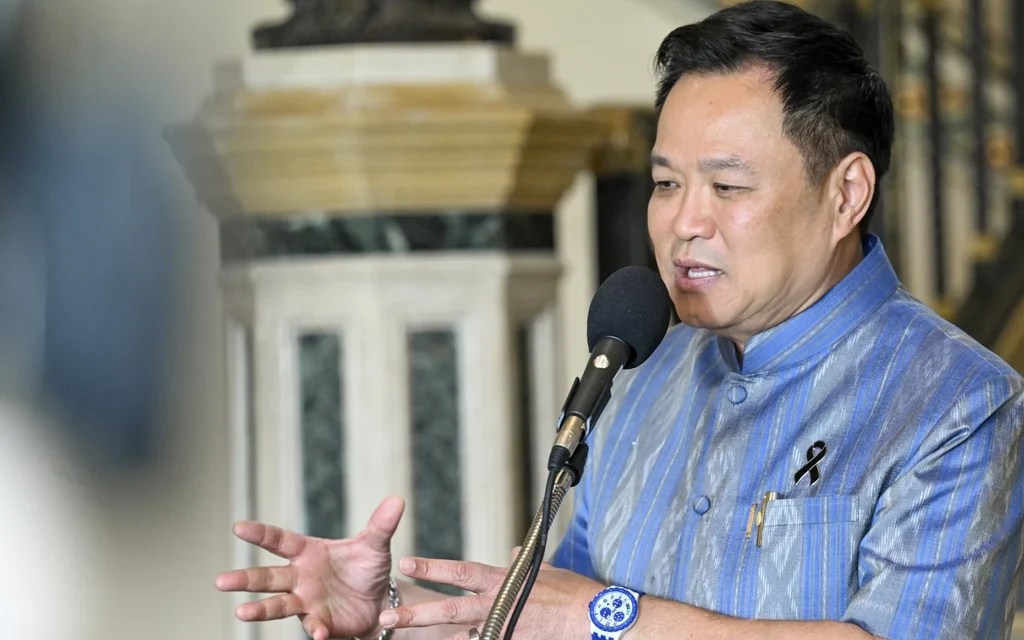 A man in blue traditional clothing speaks into a microphone.