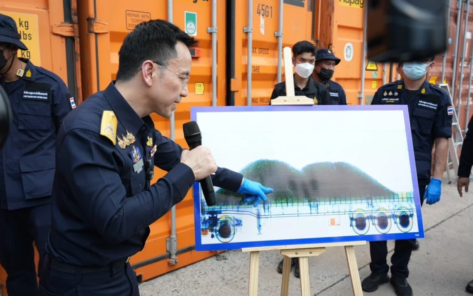 Customs officials present an image of a truck beside shipping containers.
