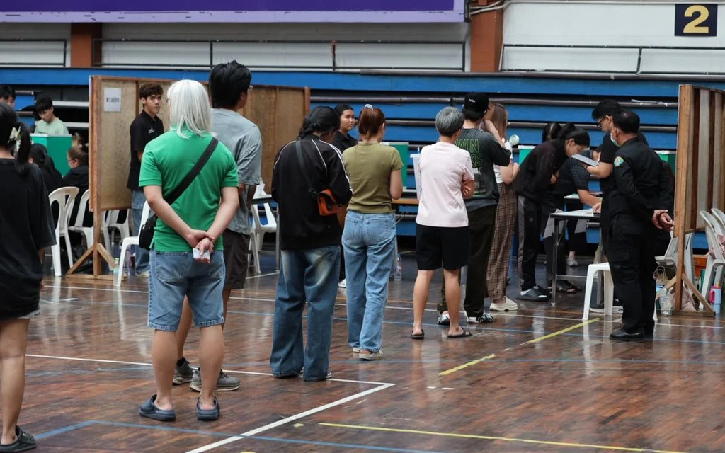 People standing in a queue at a voting station.