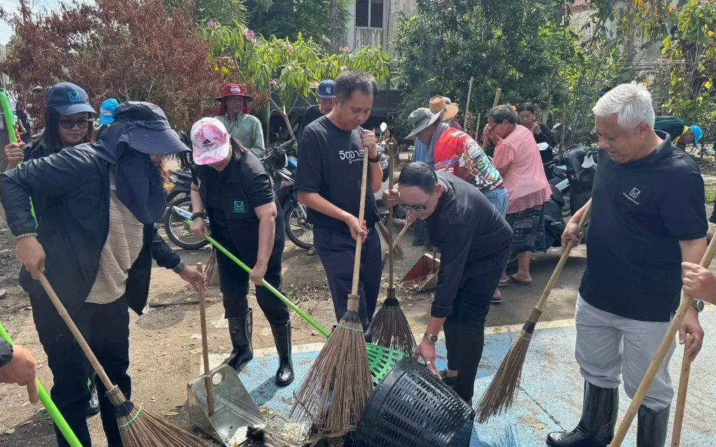 People clean mud and debris from a flood-hit housing project.