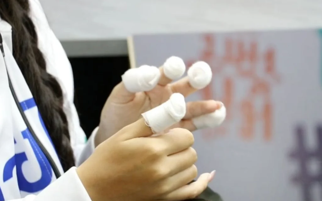 Close-up of a person with bandaged fingers holding a small object