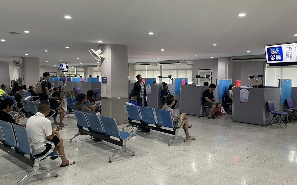 People wait at service counters in a public office.