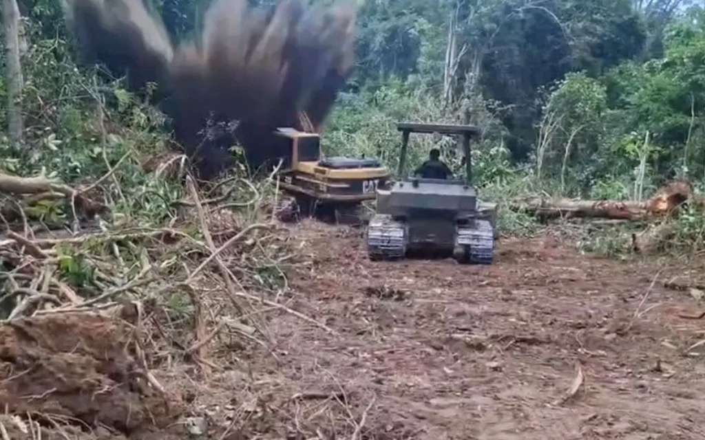 Backhoe and tracked vehicle in a forest after a mine explosion.