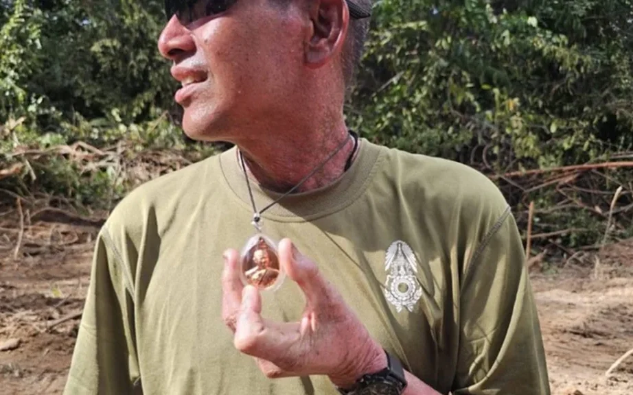 Man outdoors wearing sunglasses and holding a pendant.