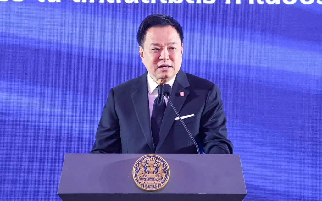 Thai prime minister speaking at a podium against a blue backdrop